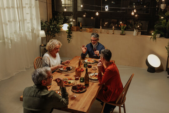 Group of Senior Friends Celebrating with Dinner and Wine at Home