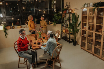 Senior friends celebrating together enjoying pension with wine and food