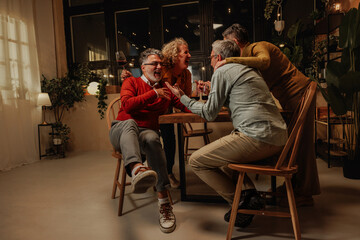 Obraz premium Group of senior friends laughing and having fun celebrating pension at home