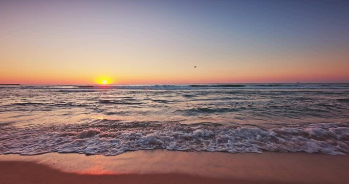 sunset over ocean beach shore with splashing waves on the sand. Sea sunrise