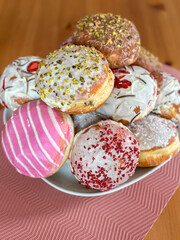 Colorful Donut Assortment A delicious assortment of donuts stacked on a white plate placed on a textured pink napkin