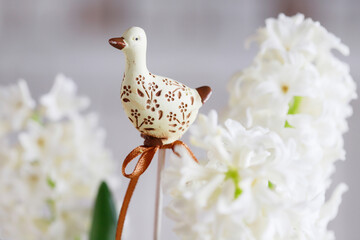 A figure of a goose on a stick among a bouquet of white hyacinths. Easter symbol, postcard motif.