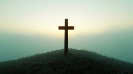 Naklejka premium A wooden cross silhouetted against a misty sunrise on a hilltop, symbolizing Easter and spirituality