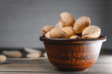 Delicious nut shaped cookies with boiled condensed milk on a wooden background
