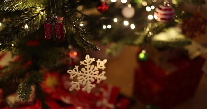 Close-up video of a beautifully decorated Christmas tree adorned with glowing lights, festive ornaments, and delicate snowflake decorations. 