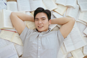 Young man relaxing among books in a creative study space during daylight hours