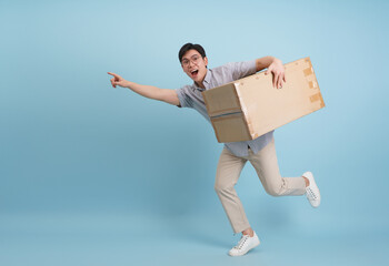 Excited young man runs with a package, pointing enthusiastically against a blue background
