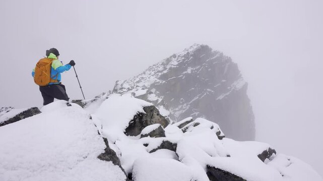 Rear view of lone mountaineer hiking a rocky mountain ridge covered with a first snow fall of the winter season. This shoot demonstrates solicit hiking in the Norwegian mountains.