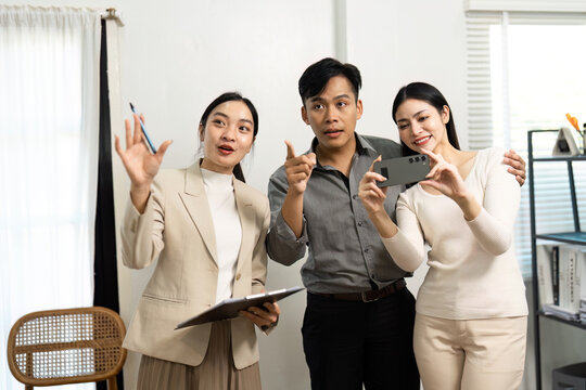 Dynamic real estate team discussing property features and capturing moments with a smartphone.