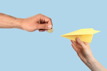 Find sponsor. Man offering coin to woman with paper plane on light blue background, closeup