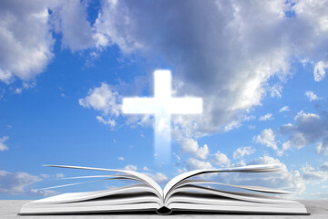 Open book with cross against the cloudy sky. Religious concept
