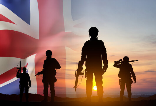 Silhouettes of a soldiers with United Kingdom flag against the sunset. Background for Remembrance Day. United Kingdom Armed Forces concept
