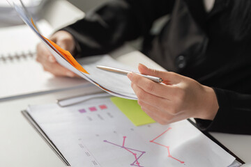 Business Growth and Data Analysis. A business professional analyzing data trends while referring to...