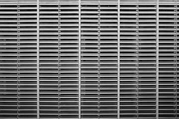 A black and white image showcasing a tightly cropped, symmetrical view of a large metal vent or...