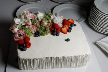 White square cake with fresh flowers and berries