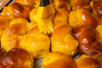 Kitchen brush smearing honey syrup on sfintisori .Romanian cuisine. Homemade Mucenici, traditional desserts made in the figure 8, smeared with honey and chopped nuts