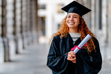 Portrait of a smiling young woman celebrating her graduation day holding her diploma in a...