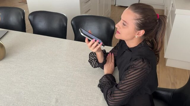 Mulher faz comunica&ccedil;&atilde;o com celular trabalhando em casa 