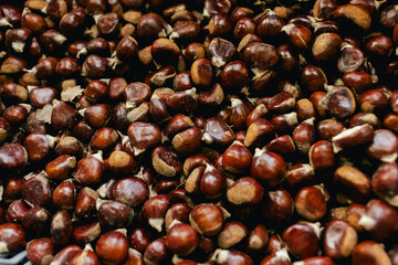 Sweet whole chestnuts in a paper bag for grill. Baked roasted healthy tasty chestnuts, autumn and Christmas vegetarian food. Traditional delicacies in Portugal. Close-up, top view
