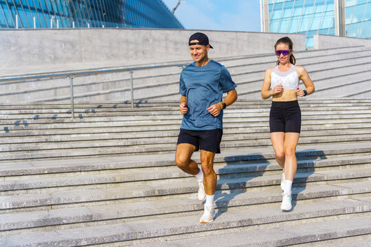 Couple jogging down stairs at a modern urban location during a sunny day