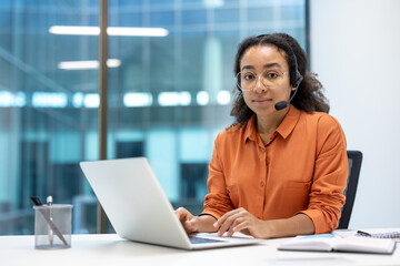 Portrait of serious focused woman with headset, customer support worker inside office at workplace,...