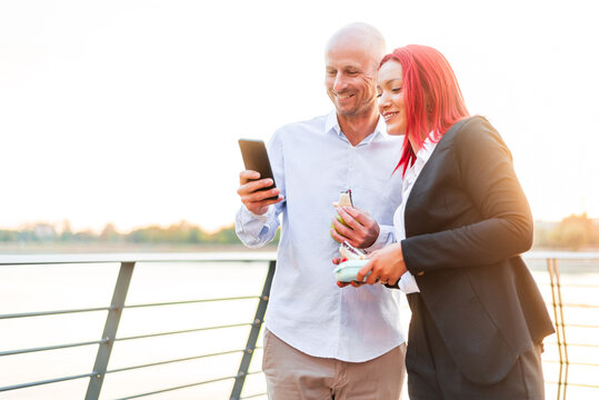 Business people having lunch break outdoors using smartphone