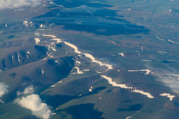 flight over the clouds. view of the clouds from the airplane window. snowy mountains and mountain slopes aerial view