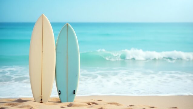 Two surfboards are standing on a sandy beach next to the ocean. Waves are gently crashing on the shore, and the clear sky offers a perfect day for surfing