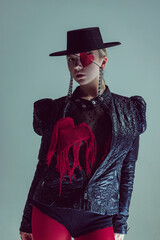 Close-up portrait of young woman in black wide-brimmed hat, leather jacket, and red heart eyepatch,...