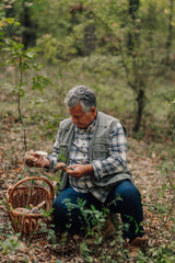 Senior mycologist examining wild mushrooms in forest
