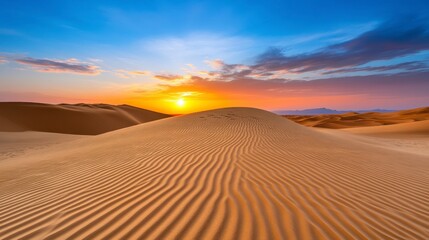 Vibrant sunset over undulating sand dunes in a desert landscape. Golden hour light illuminates the textured sand, creating a warm and serene atmosphere.