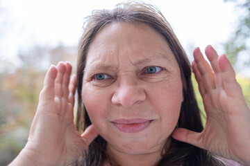 Woman covering ears with pained expression, Emotional portrait showing discomfort loud noise,...