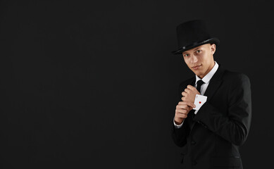 Illusionist taking playing card out of sleeve on black background, space for text