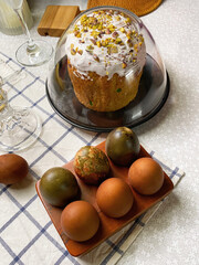 Easter table setting with Easter cupcake in white frosting and painted eggs on wooden stand. Family traditions of Easter, cooking recipes, baking
