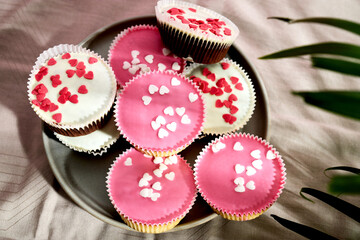 Sponge cake cupcakes with icing and decorated with sugar sprinkles in the shape of hearts