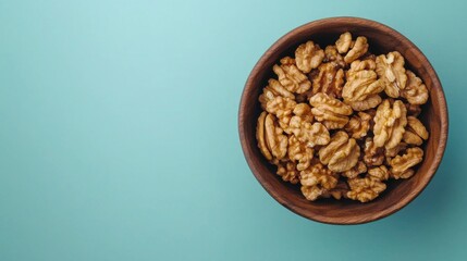 Fototapeta premium Walnut kernel halves, in a wooden bowl. Close-up, from above on colored background. Healthy eating Walnut concept. Super foods with copy space.