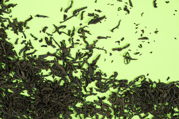 Loose black tea scattered on green background