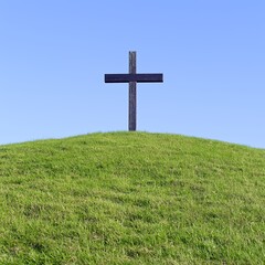 Dark Wooden Cross on Green Hill Under Blue Sky