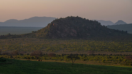 koniec dnia, słońce za horyzontem ostatnimi promieniami oświetla Park Narodowy Tsavo i rezerwat wzgórz Taita, Kenia, Afryka © Kamil_k2p