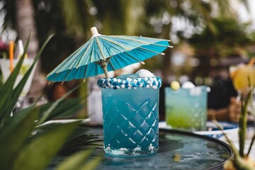 Enjoying a refreshing blue lagoon cocktail under the sun at a tropical beach bar with friends on a warm afternoon