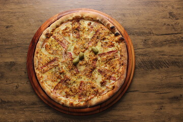 cheese pizza with bacon, fried garlic and olives on wooden table