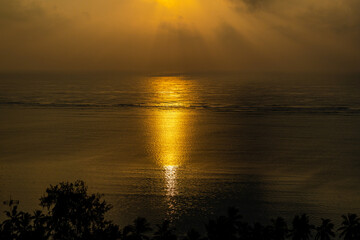 bajeczny w schód słońca nad oceanem indyjskim, spokojne wody odbijają poranne promienie a przybrzeżne tropikalne palmy uzupełniają piękny widok © Kamil_k2p