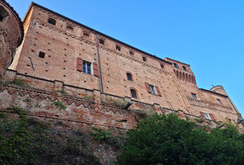 The historic brick castle fortress of Bardassano with clear blue sky in a serene landscape during late afternoon light.