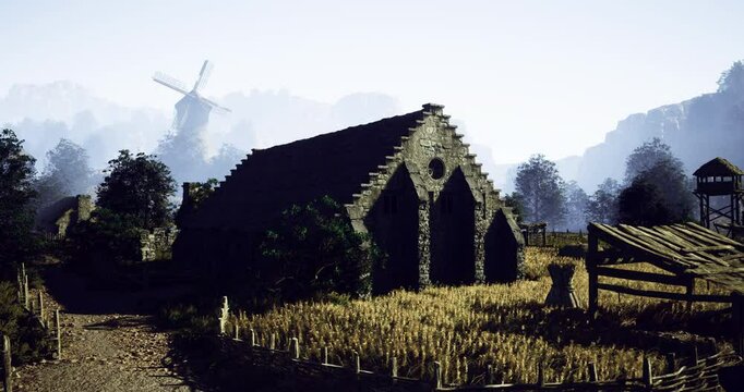 A historic stone barn stands amidst tall grasses, with a traditional windmill in the distance. Surrounding trees add to the serene countryside atmosphere on a clear day.