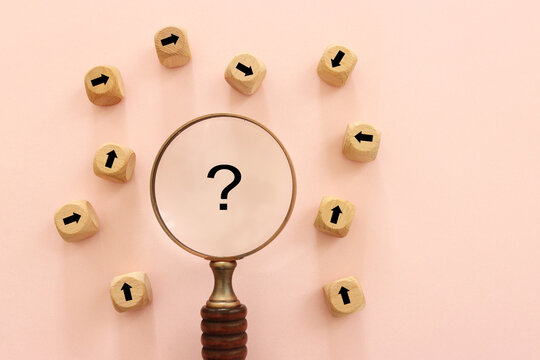 Magnifying glass, question mark and wooden cubes with arrows