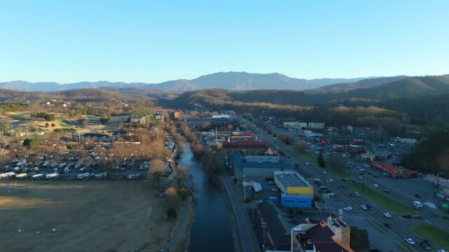 Drone shot pulling out and panning to reveal the Smoky Mountains outside of Downtown Piegon Forge, TN.