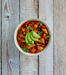 shredded chicken soup topped with fresh avocado and cilantro