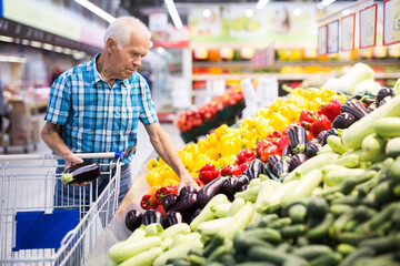 Old age man choosing eggplant in supermarket