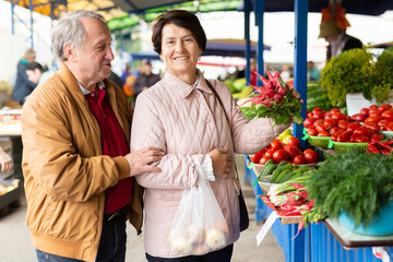 Elderly man and woman buying radishes at an open market