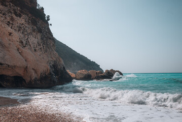 Fototapeta premium Rocky coastline with turquoise waves crashing on the shore in Kefalonia, Greece